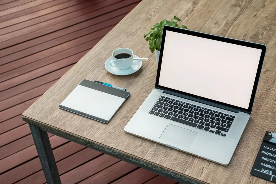 Un homme retouche une image de fruits sur un MacBook Pro, assis dehors sur l’herbe.